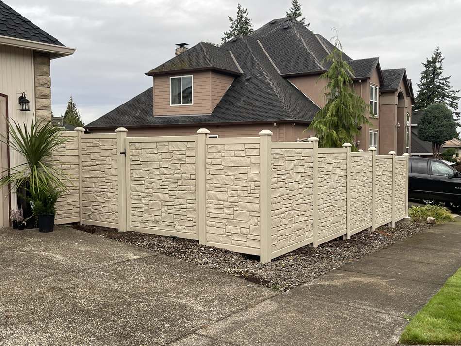 Composite stone-look privacy fence with driveway view by Gravelle Construction