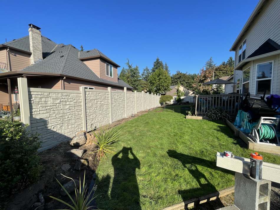 Composite stone-look privacy fence along backyard lawn by Gravelle Construction
