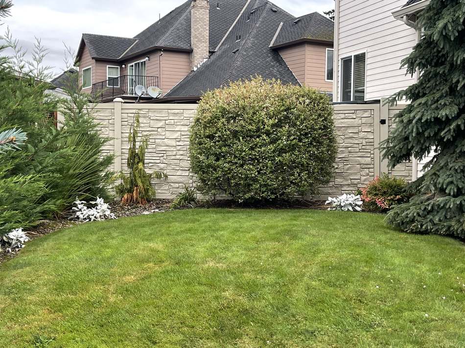 Composite stone-look privacy fence corner with gate by Gravelle Construction