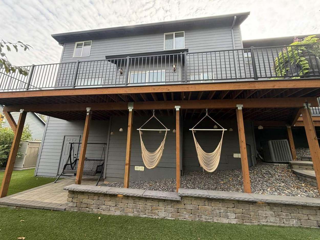 Underside of finished two-tier deck showing covered lower patio with hammocks and retaining wall