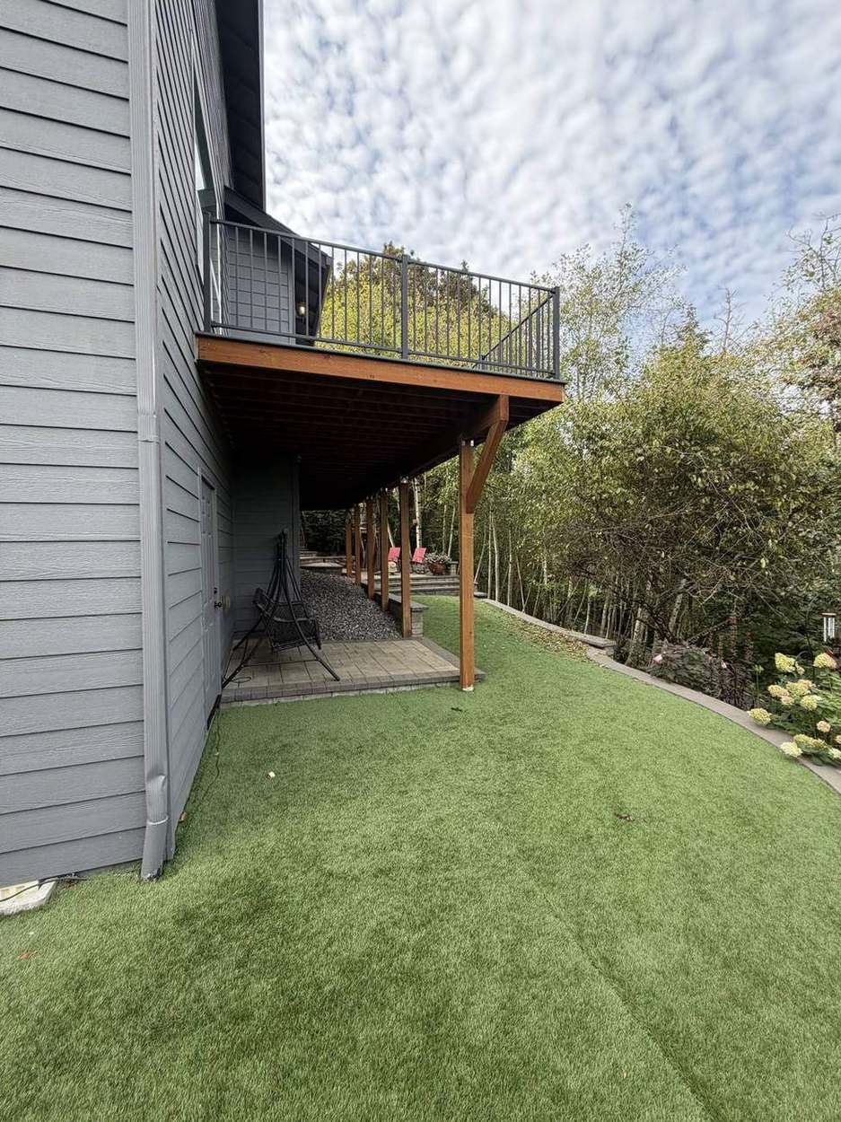 Finished two-tier deck viewed from below showing black metal railing and support posts