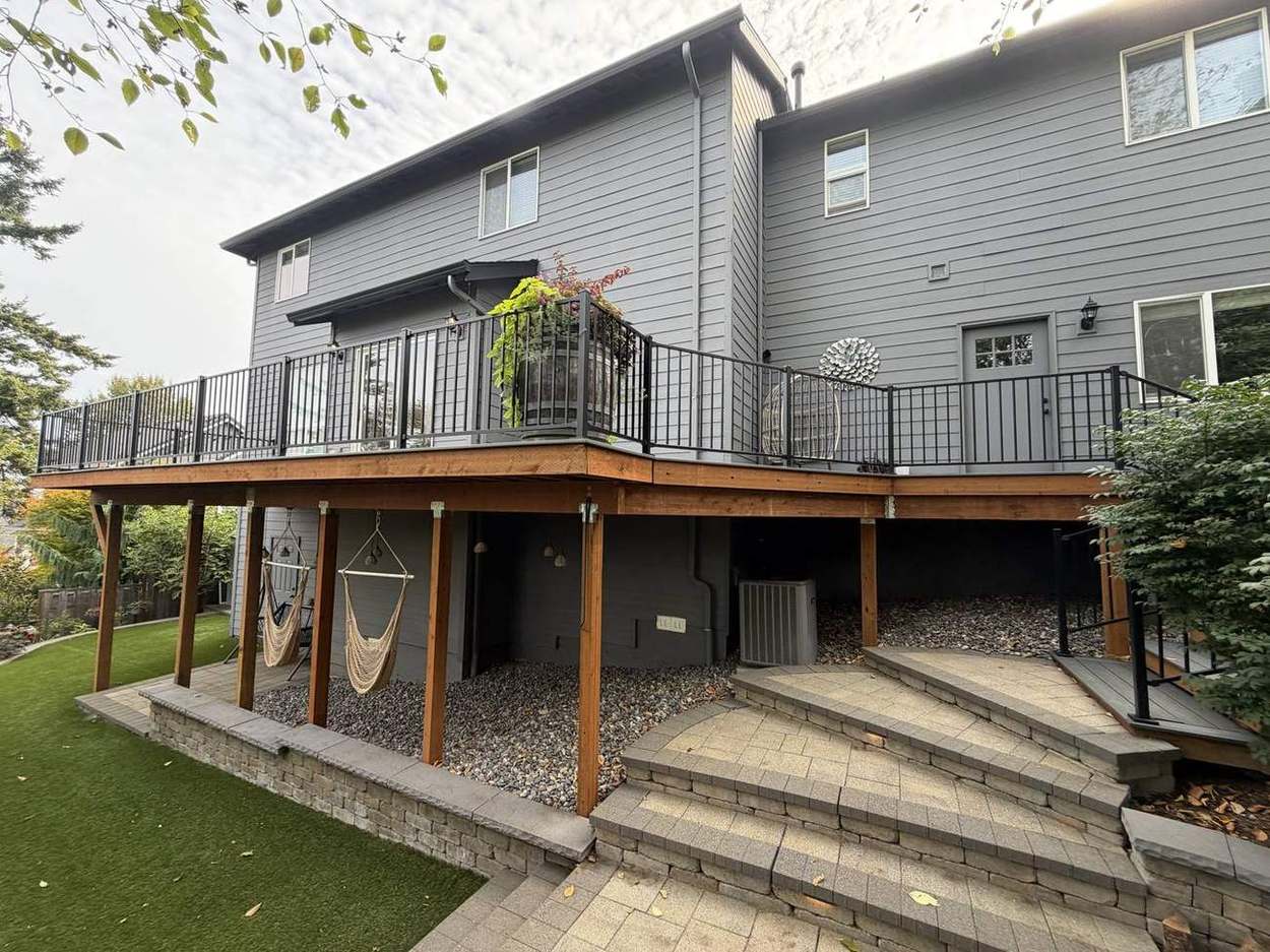 Finished upper deck with black metal railing, wine barrel planter, and egg chair by Gravelle Construction