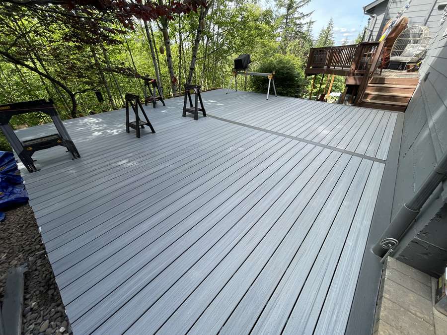 New gray composite decking installed on lower deck, with sawhorses and tools still set up