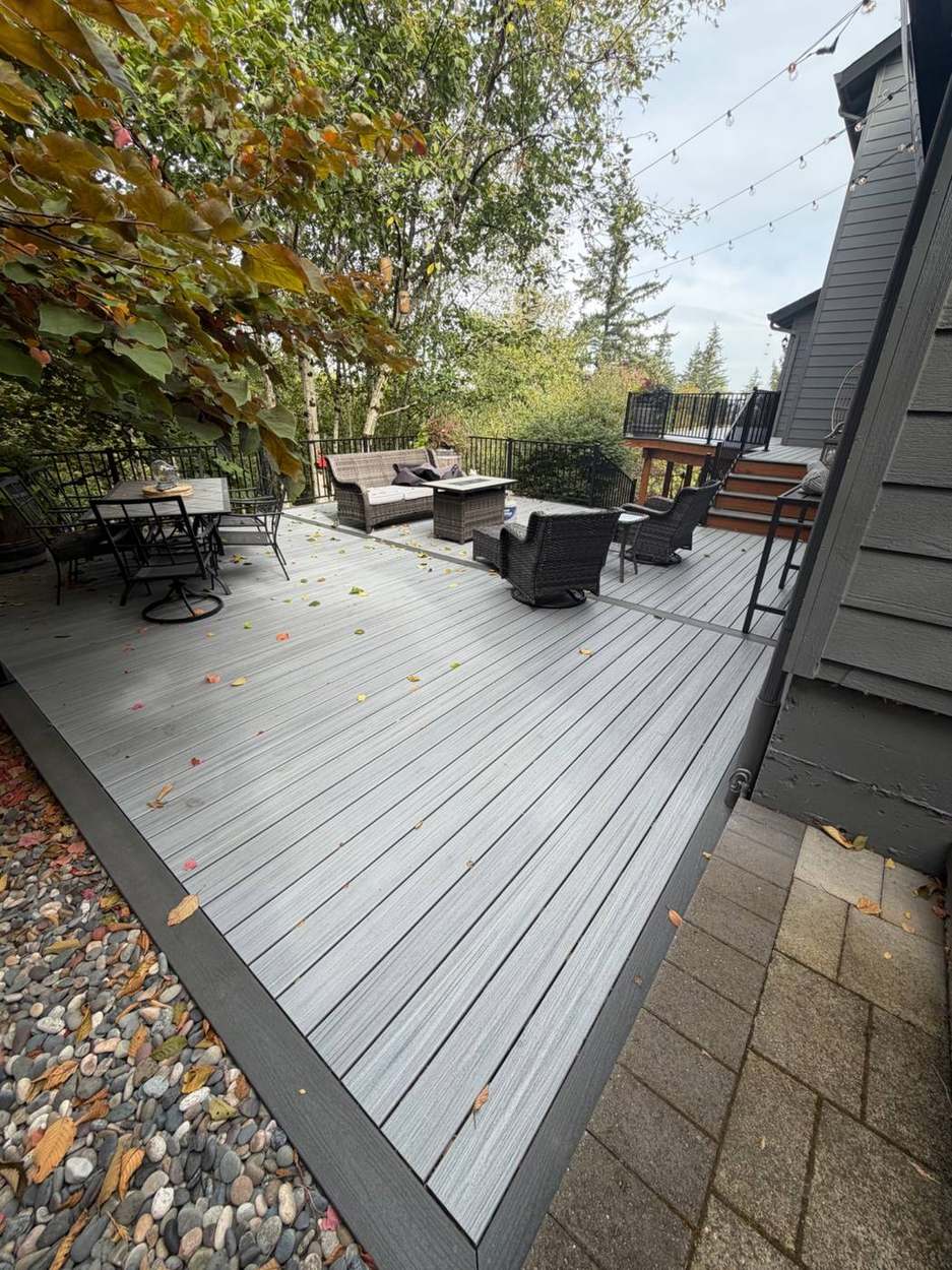 Finished lower deck patio with outdoor furniture, string lights, and stairs up to the main deck