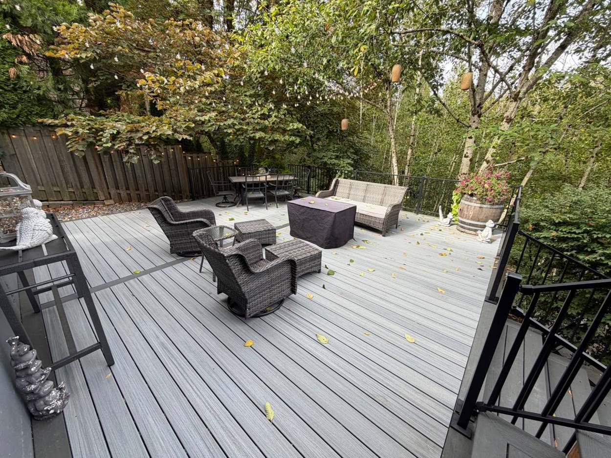 Finished lower deck patio seating area with wicker furniture, garden statues, and string lights