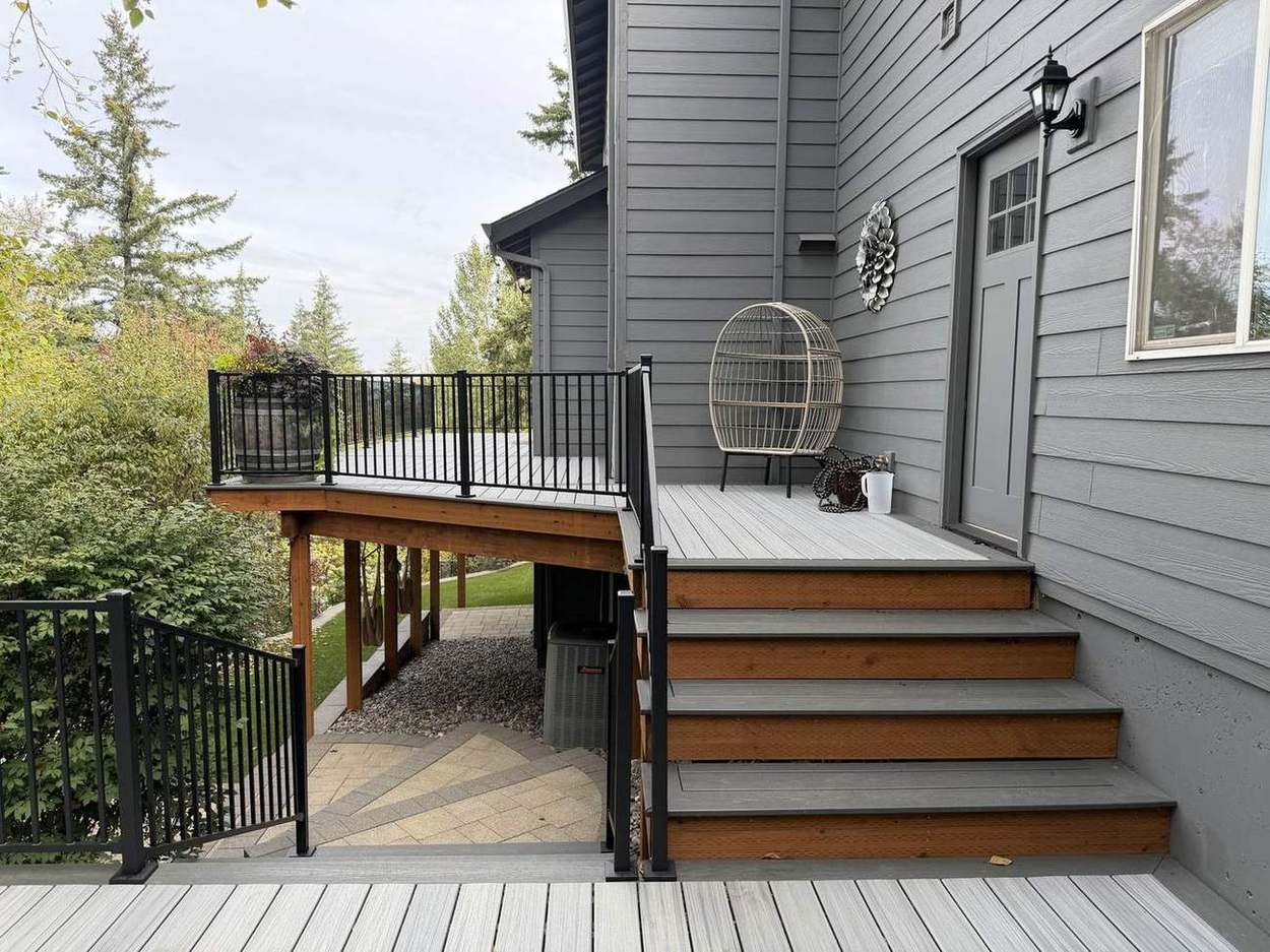 Finished upper deck landing with stairs down to paver patio and black metal railing