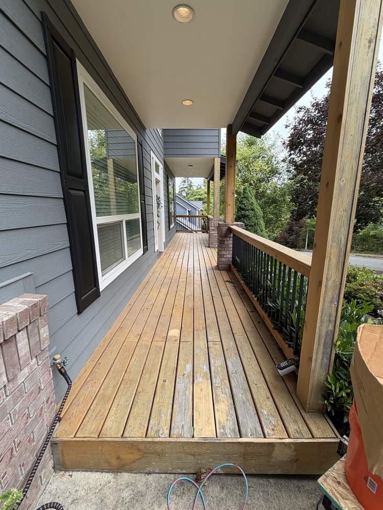 Covered front porch walkway with weathered natural wood decking before painting