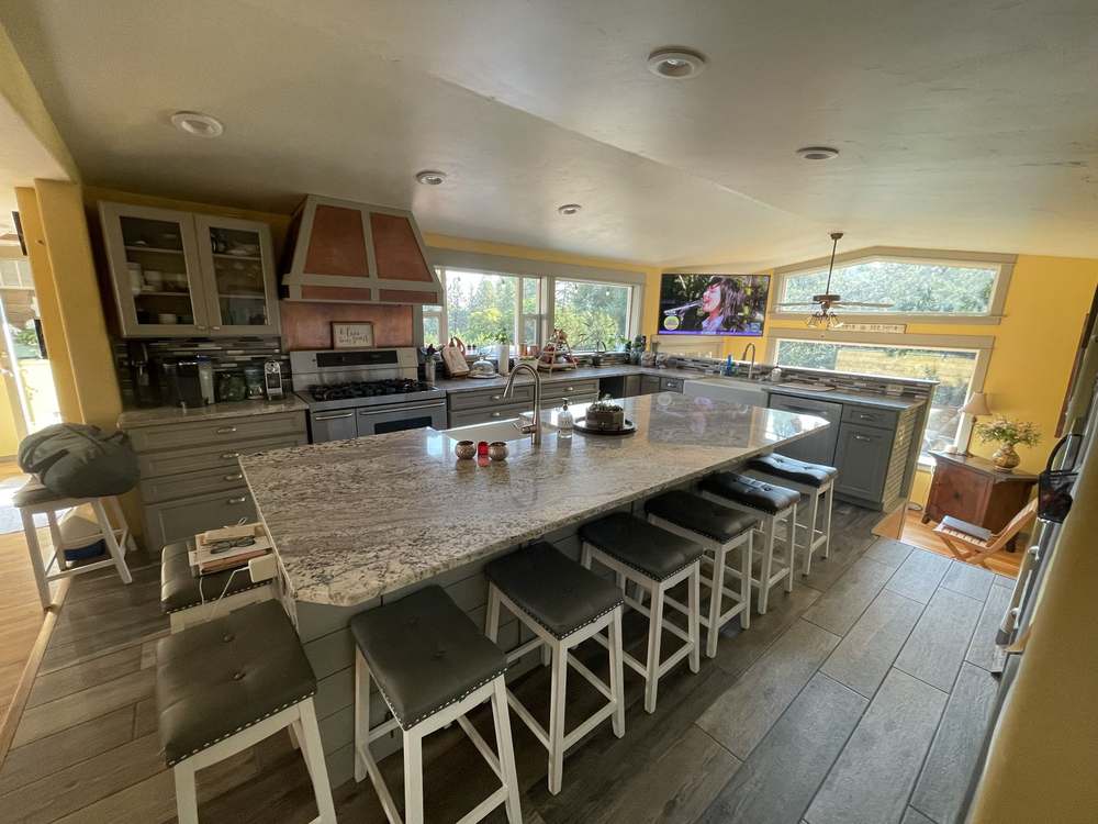 Remodeled kitchen with granite island, gray cabinetry and copper range hood by Gravelle Construction