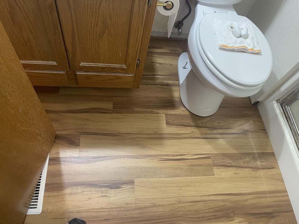 Bathroom with new wood flooring and reinstalled toilet by Gravelle Construction
