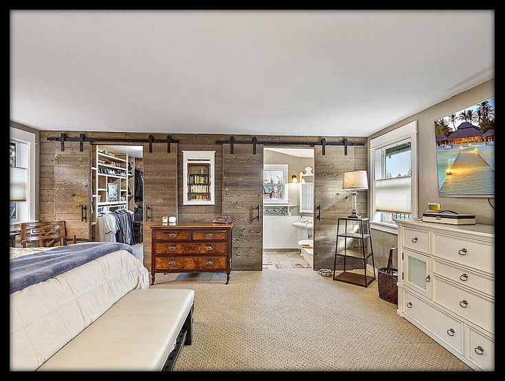 New full wood-paneled wall with double barn doors separating master bedroom, closet and bathroom by Gravelle Construction