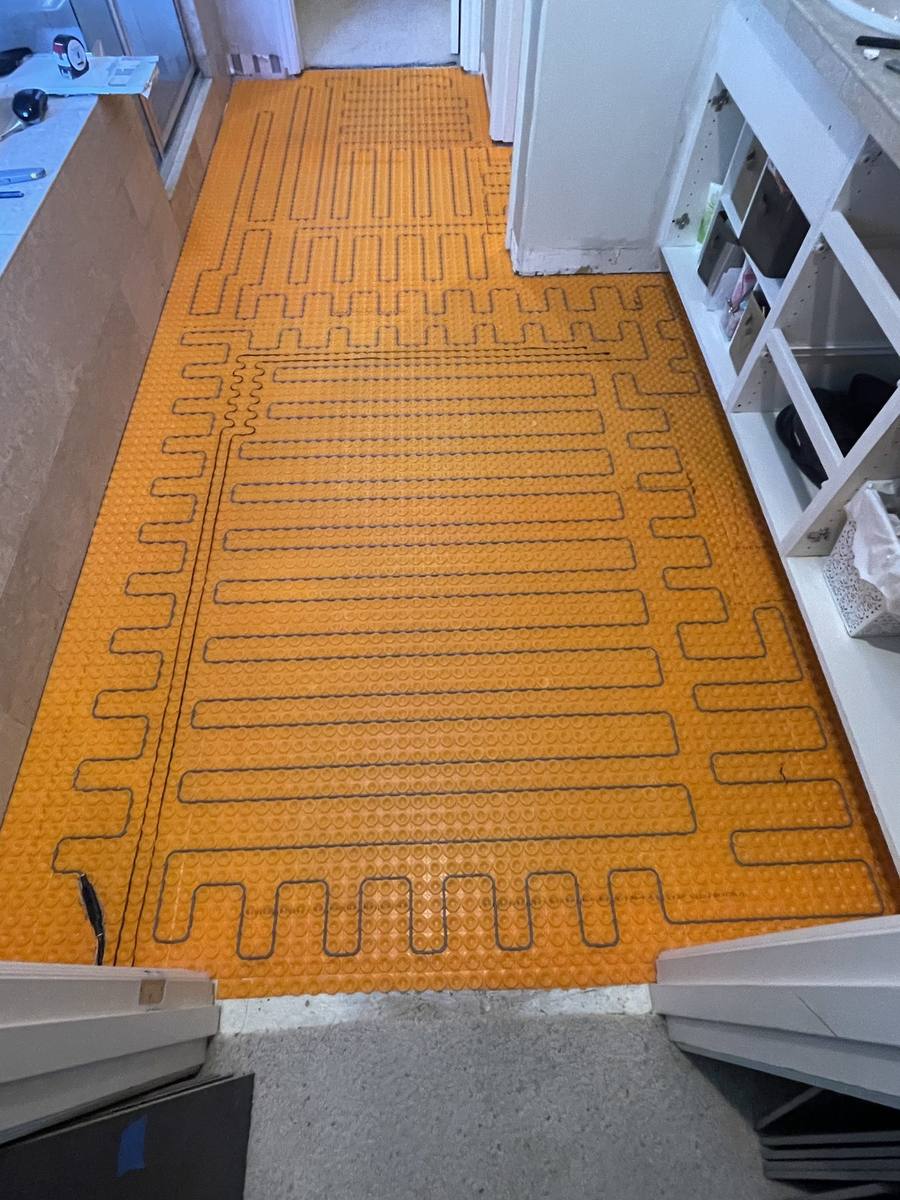 Electric heat cable installed on Ditra-Heat mat across bathroom floor before tile