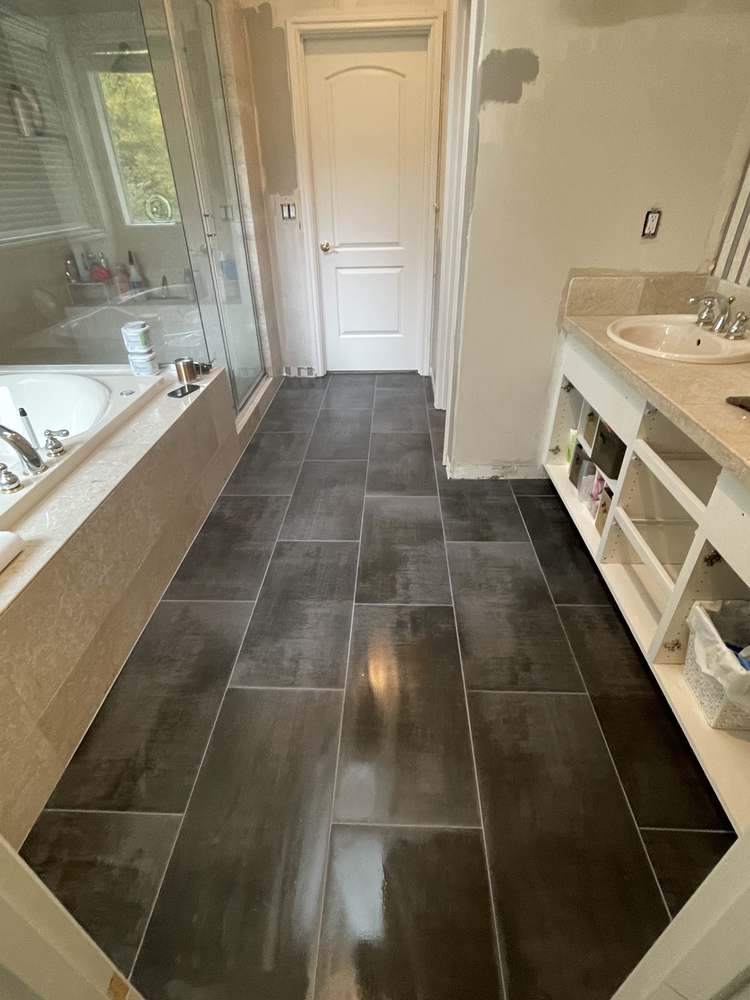 Finished heated tile floor in a primary bathroom with soaking tub and walk-in shower, by Gravelle Construction