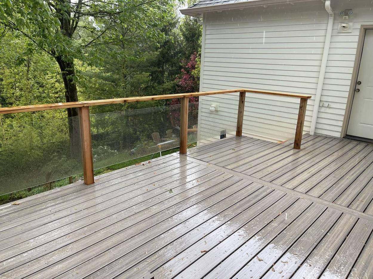 Elevated upper deck with cedar-capped glass panel railing built by Gravelle Construction