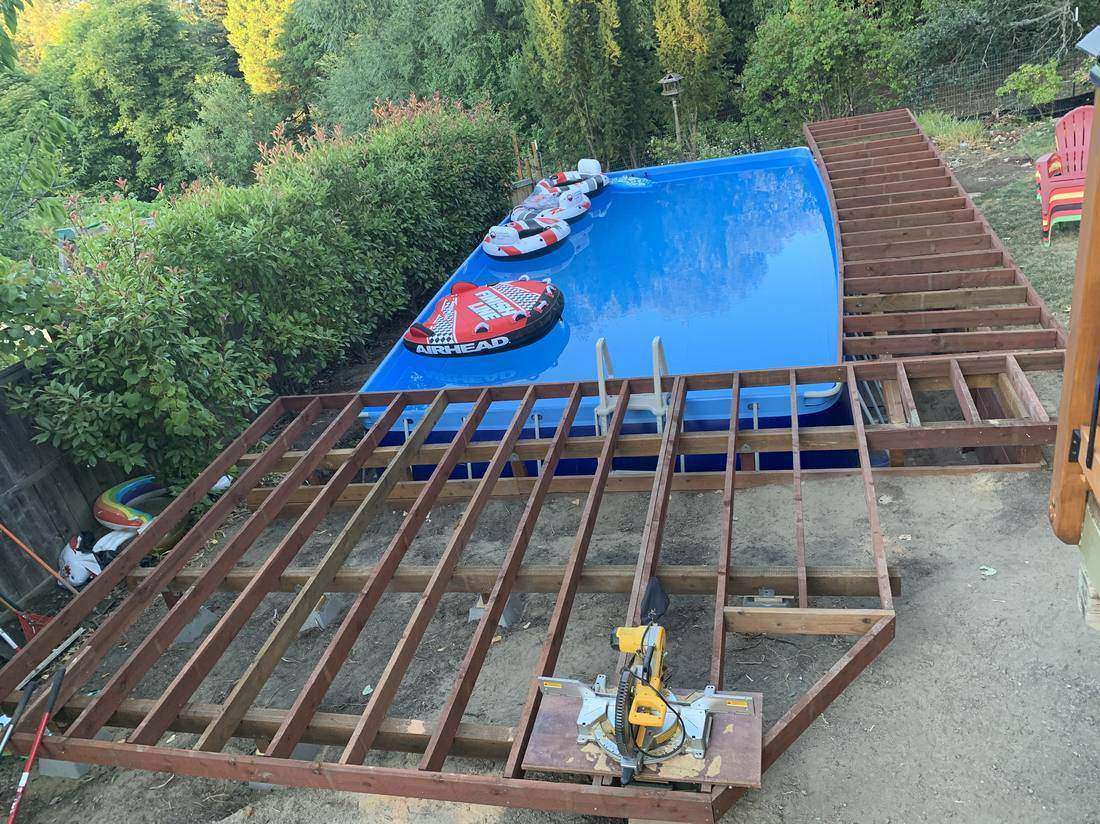 Deck framing under construction over in-ground pool