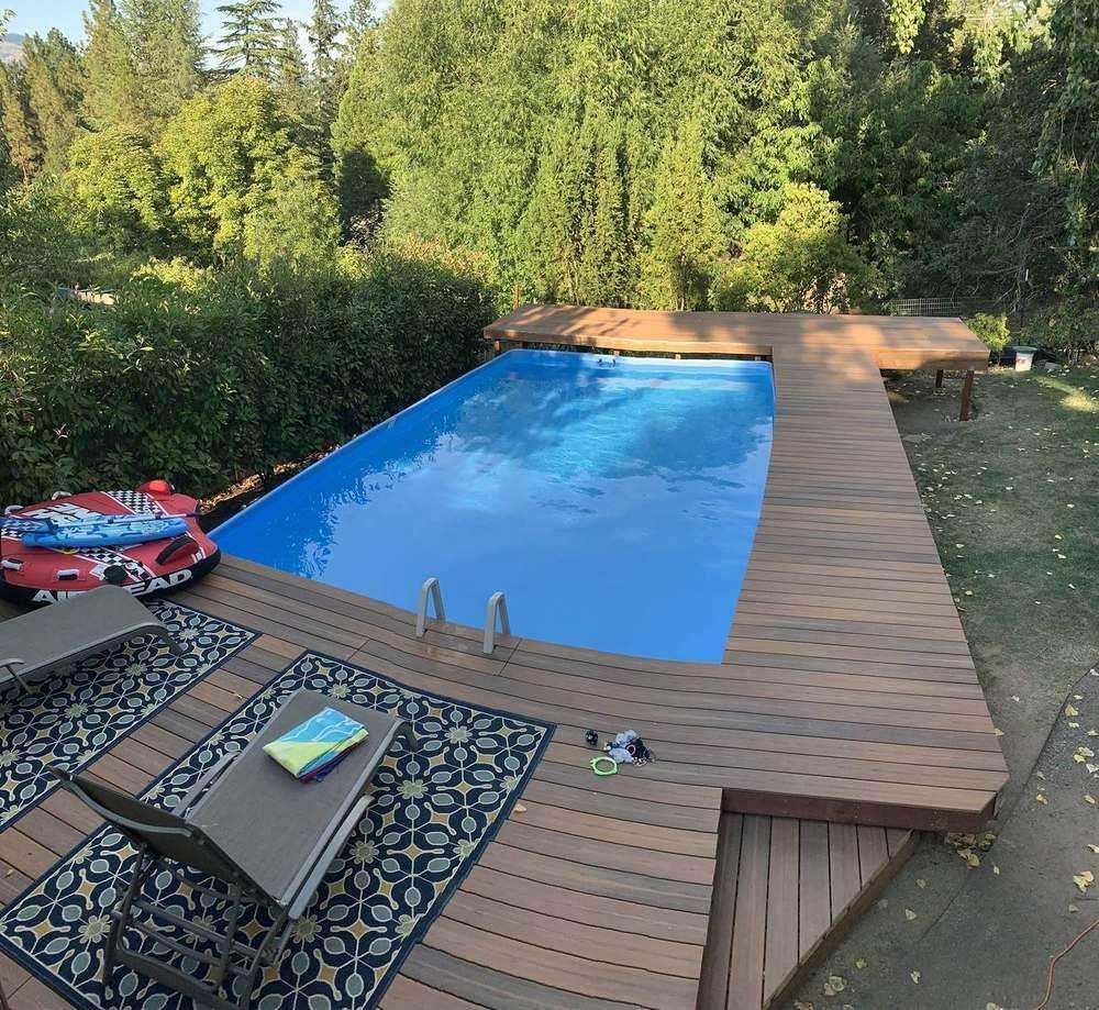 Wraparound composite deck built around an in-ground pool by Gravelle Construction