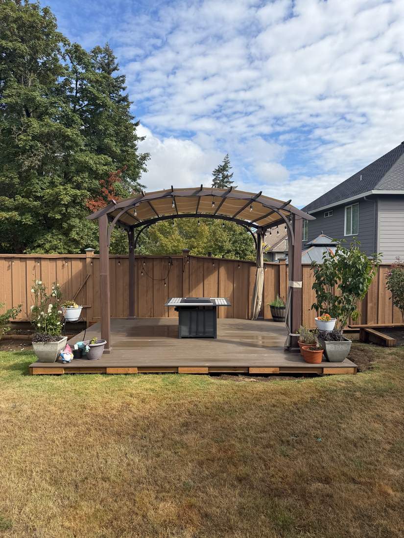 Finished backyard deck with pergola and fire table by Gravelle Construction